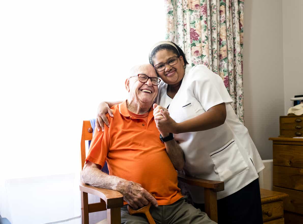 Portrait photo of a smiling senior man and nurse embracing